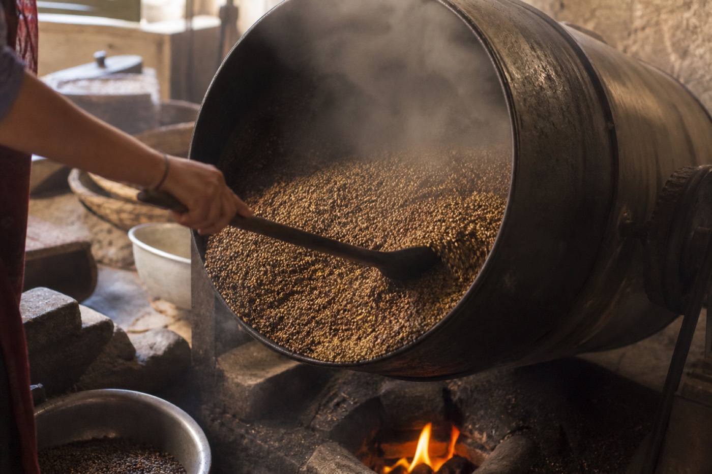 Whole spices being roasted in an iron drum